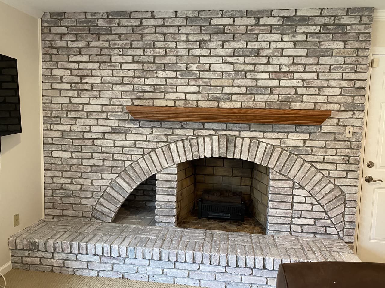Brick fireplace transformed with a whitewash finish, original texture preserved beneath a soft chalky white